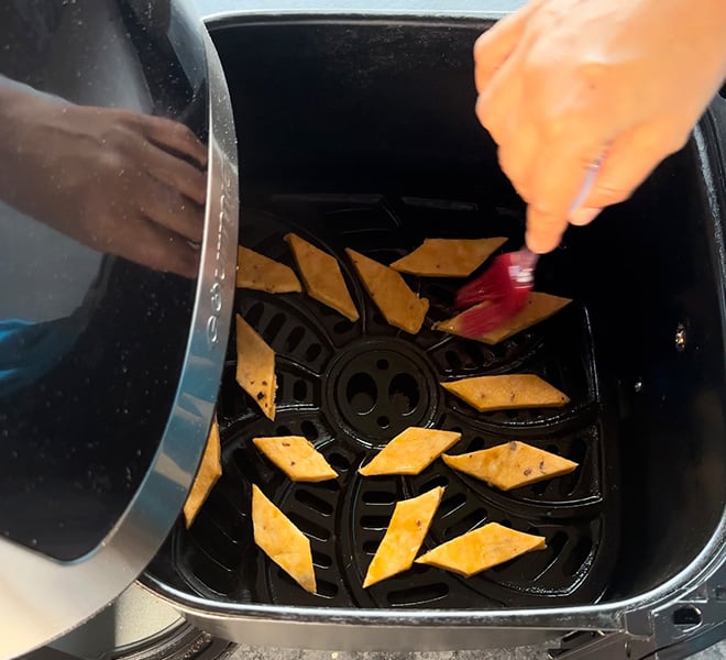 cheese namak para being brushed with oil and arranged in a single layer in an air fryer