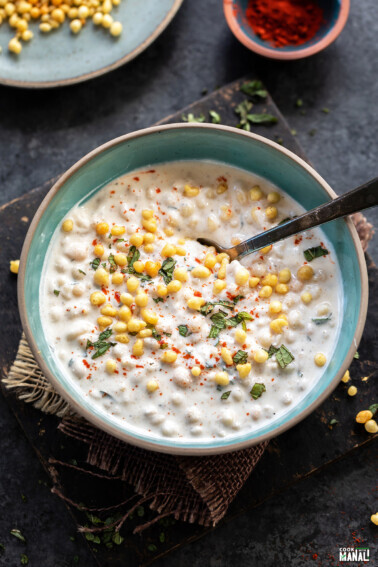 yogurt in a blue bowl topped with boondi and chopped mint