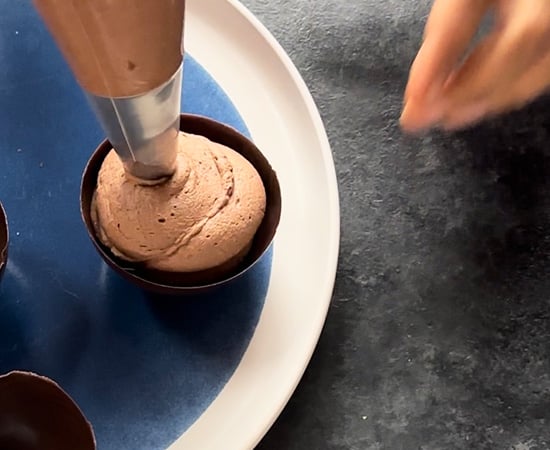 chocolate mousse being filled in chocolate cups