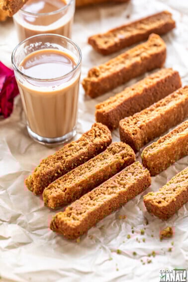 some rusk arranged on a tray with chai glasses in the background