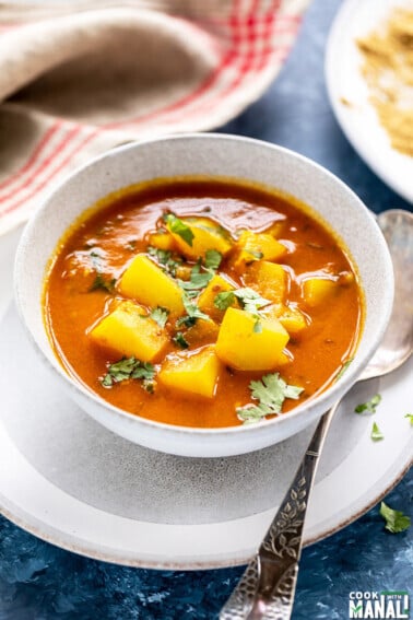 lauki curry in a white bowl with a spoon placed on the side