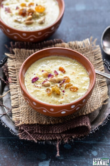 lauki kheer served in a clay bowl garnished with nuts, raisins and dried rose petals
