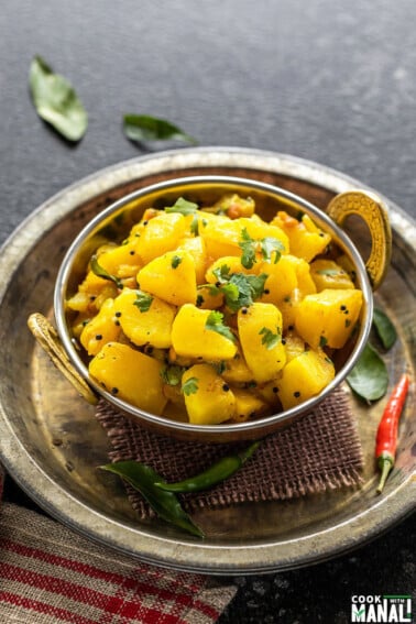 potato masala served in a copper kadai garnished with cilantro