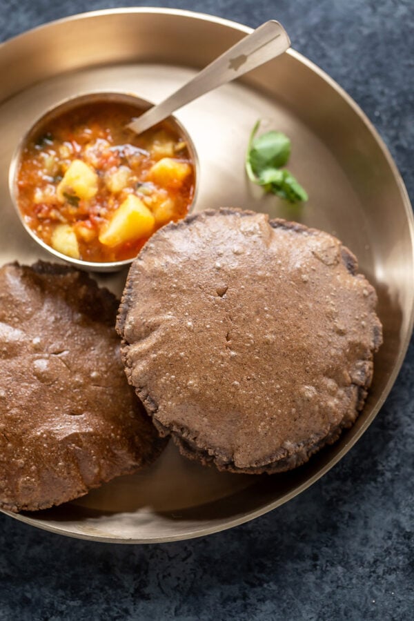 round puris served in a plate with aloo curry on the side
