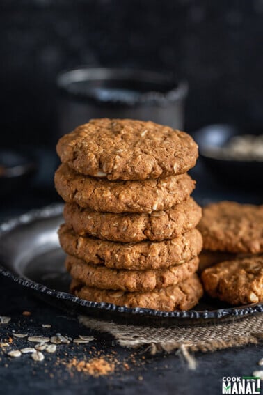stack of oats jaggery cookies with a cup in the background