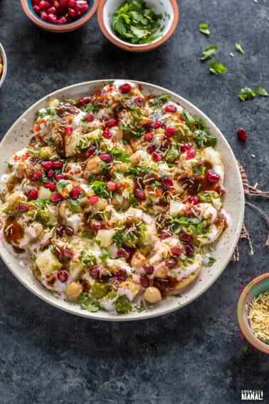 plate of papdi chaat garnished with cilantro, pomegranate, sev
