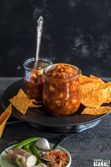 peach chutney in a small glass jar with chips on the side
