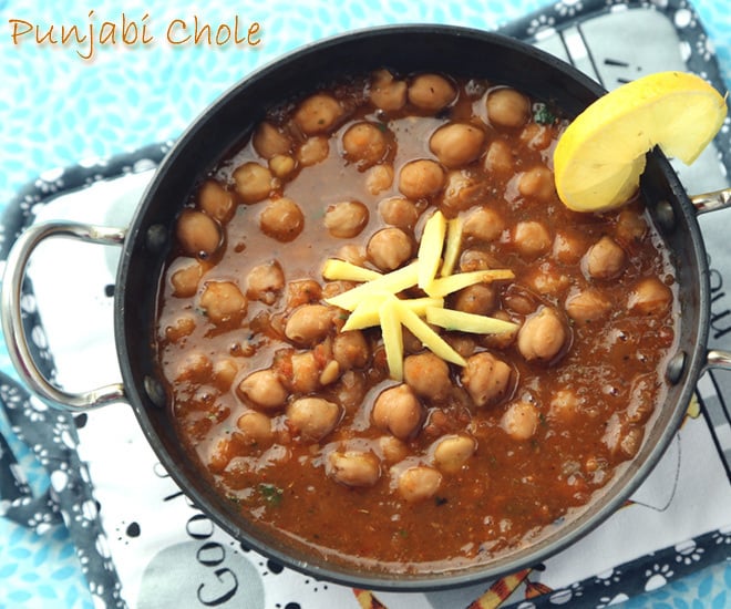 punjabi chole served in a kadai with a slice of lemon wedge on the side
