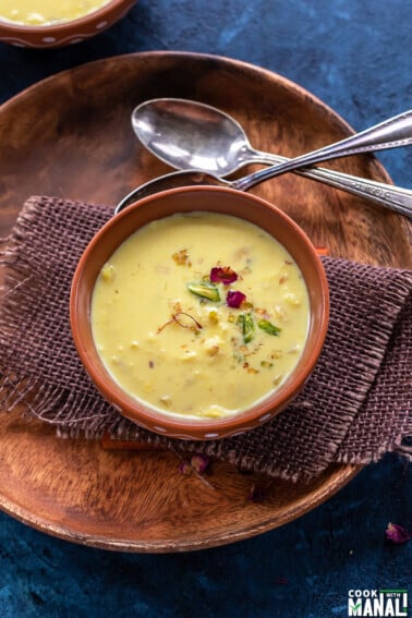 bowl with yellow color milk topped with rose petals and pistachios