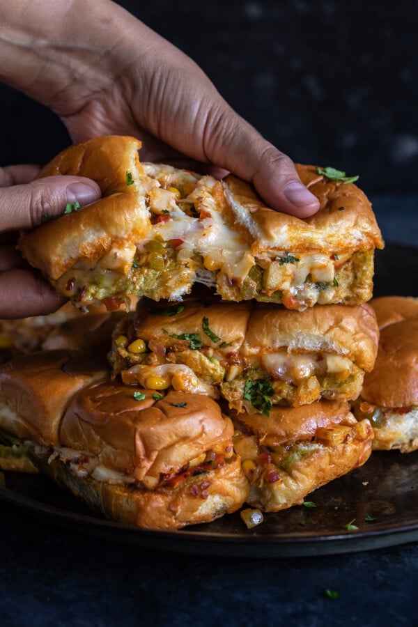 pair of hands pulling sliders apart to show the cheese pull