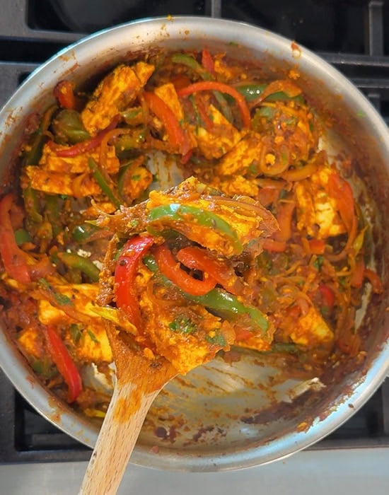 wooden spatula showing paneer curry with peppers