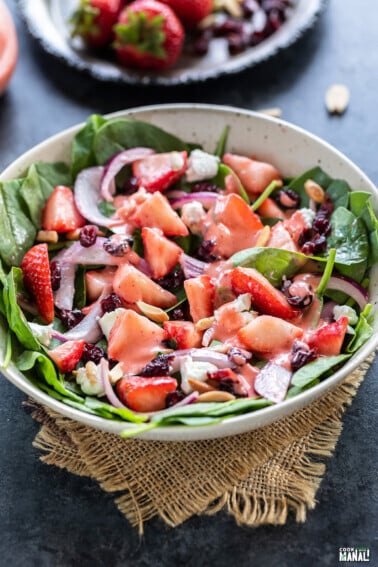 bowl of salad with spinach strawberries, almonds