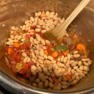 white beans in a pot with tomatoes and herbs